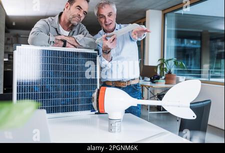 Engineer explaining wind turbine blade to colleague working at office Stock Photo