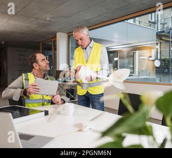 Engineers discussing over wind turbine rotor at office Stock Photo