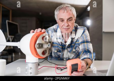 Engineer checking current of wind turbine rotor using multimeter at office Stock Photo