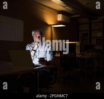 Businessman using smart phone sitting at office Stock Photo