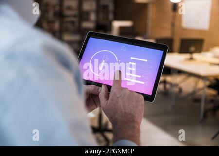 Businessman using automation app on tablet PC at office Stock Photo