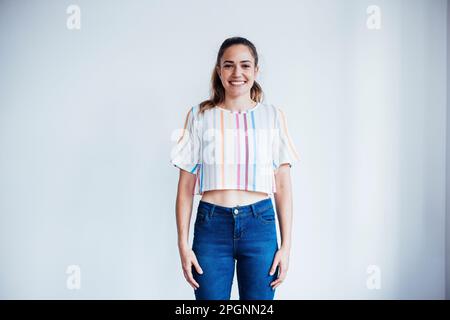 Happy businesswoman standing in front of white wall Stock Photo