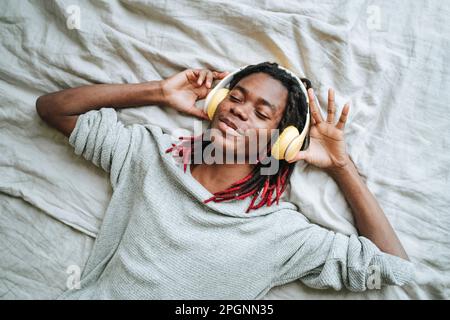 Young man with eyes closed lying on bed at home Stock Photo
