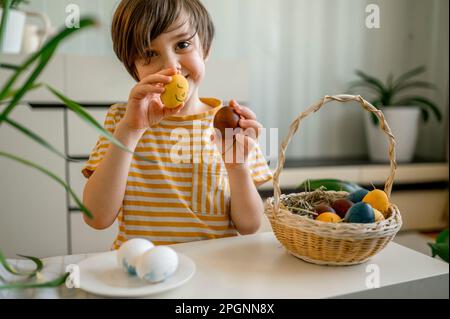Smiling boy holding decorated Easter eggs at home Stock Photo