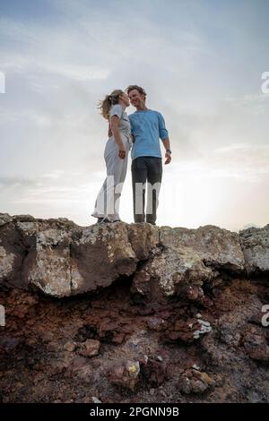 Smiling young couple standing on edge of cliff Stock Photo