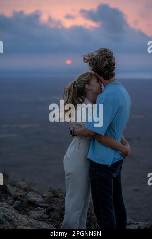 Romantic woman embracing boyfriend at sunset Stock Photo