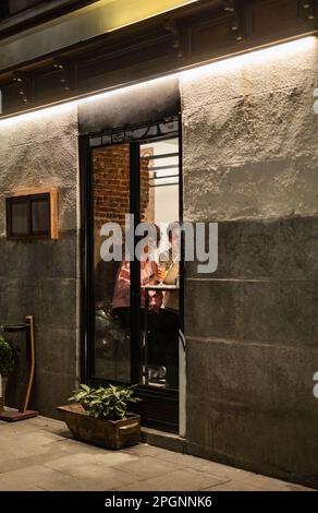 Friends having dinner seen through window of restaurant Stock Photo