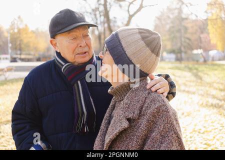 Senior man with arm around woman at autumn park Stock Photo