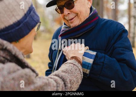 Senior woman holding hand of man wearing sunglasses at park Stock Photo
