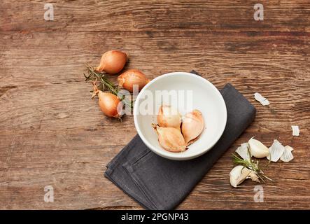 Studio shot of bowl, raw onions, garlic and rosemary Stock Photo