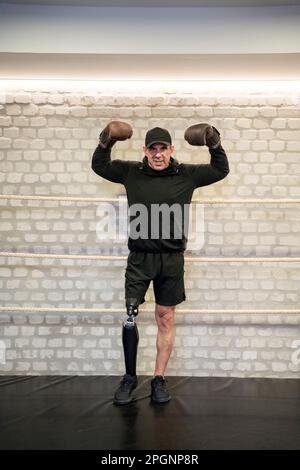 Confident man with artificial limb flexing muscles in gym Stock Photo