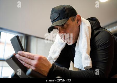 Focused man wearing cap using smart phone in gym Stock Photo