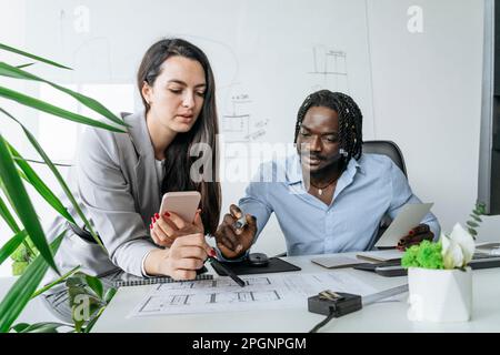 Architect and colleague discussing over blueprint at office Stock Photo