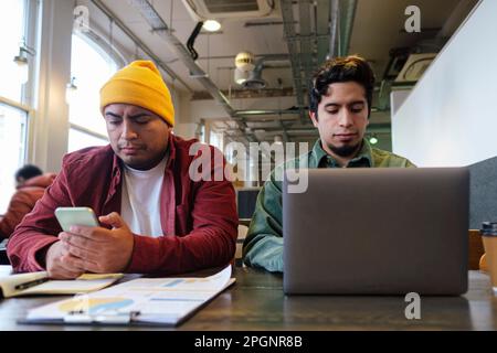Freelancers working on laptop and using smart phone in cafe Stock Photo