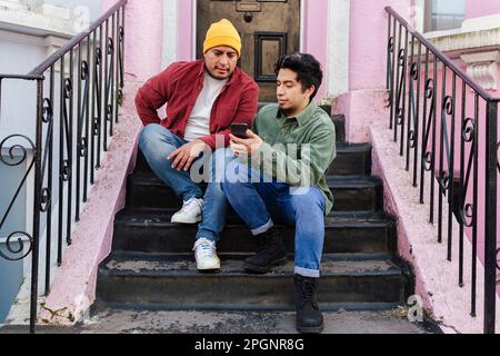 Man with brother using smart phone at steps Stock Photo