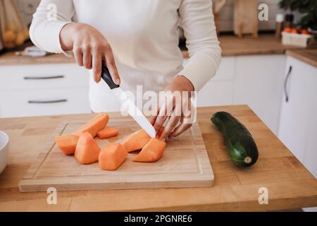 Hands of woman cutting vegetables in kitchen at home Stock Photo