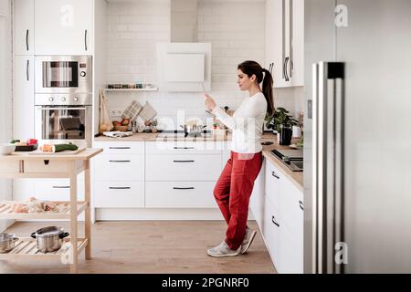 Woman using tablet PC standing in kitchen Stock Photo