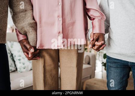 Family holding hands together at home Stock Photo