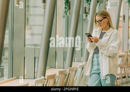 Businesswoman surfing net through smart phone at cafe Stock Photo