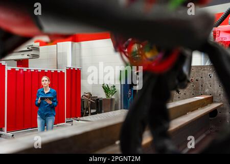 Mature technician with tablet PC working in robot factory Stock Photo