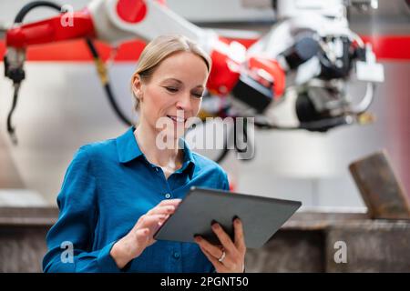 Technician using tablet PC in robot factory Stock Photo