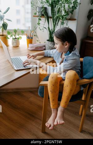 Girl using laptop sitting at table in home Stock Photo