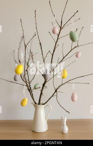 Easter eggs hanging on twigs in vase at home Stock Photo
