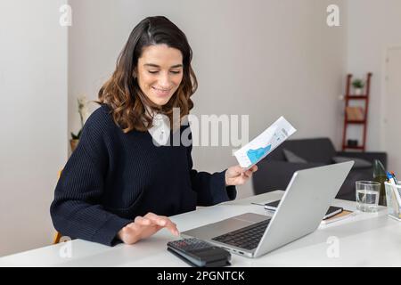 Businesswoman with document using calculator at desk Stock Photo