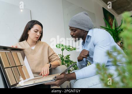 Interior designer discussing with colleague over wooden color swatches in office Stock Photo