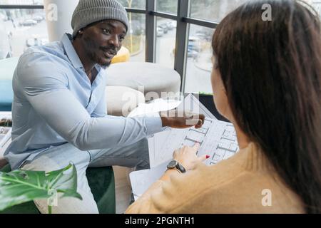 Young architect discussing with colleague over documents at office Stock Photo