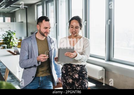 Businessman discussing with colleague using tablet PC at office Stock Photo