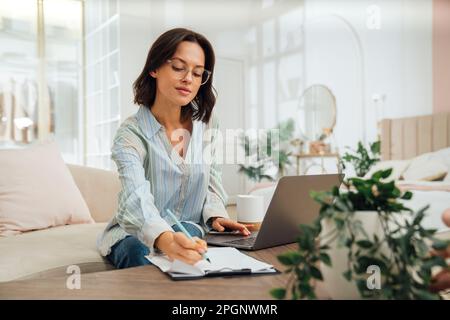 Freelancer writing on paper with pen and working at home Stock Photo