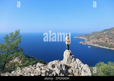 Hiker standing on edge of cliff looking at sea Stock Photo