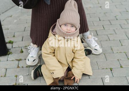 Woman with son sitting on footpath Stock Photo