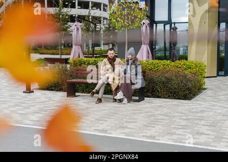 Man and woman sitting on bench with son at footpath Stock Photo