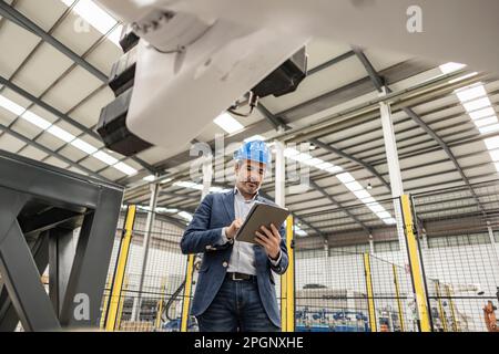 Engineer wearing hardhat using tablet PC in factory Stock Photo