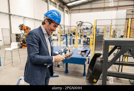 Engineer wearing hardhat using tablet PC at industry Stock Photo