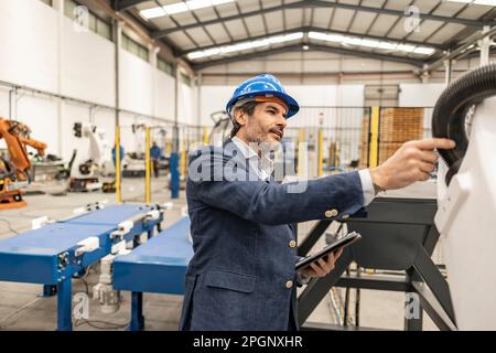 Engineer wearing hardhat examining machinery parts in factory Stock Photo