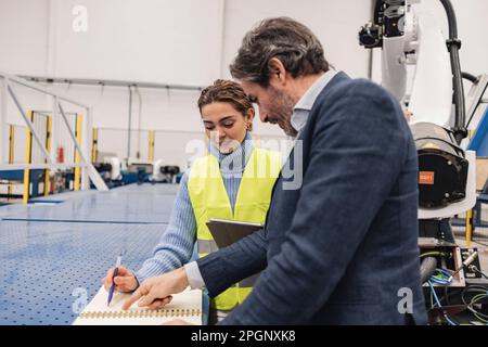 Engineers explaining over note pad working in factory Stock Photo
