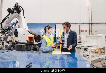 Engineers having discussions standing in robotics factory Stock Photo