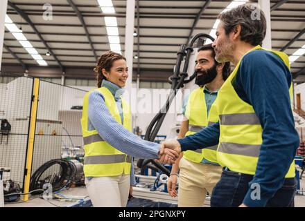 Engineer shaking hand with colleague in factory Stock Photo