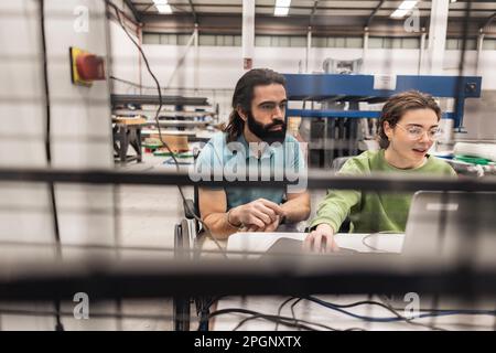 Engineers working on laptop in factory Stock Photo