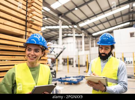 Smiling engineer with colleague making notes in factory Stock Photo