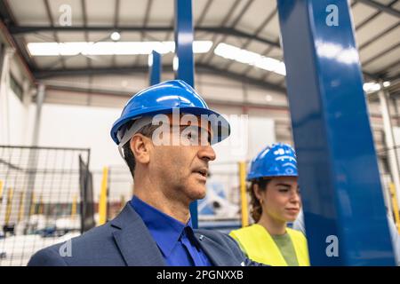 Engineer and colleague wearing hardhats in factory Stock Photo