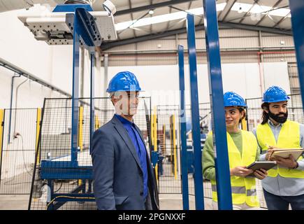 Thoughtful engineer with colleagues in factory Stock Photo