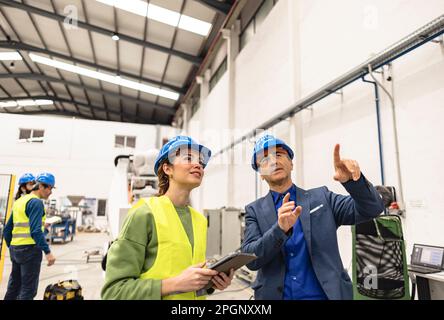 Smiling engineers having discussion in robotics factory Stock Photo