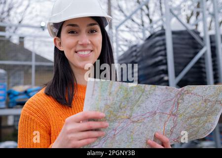 Smiling young woman with map at site Stock Photo