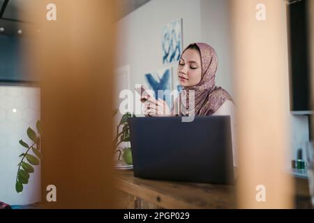 Freelancer text messaging through smart phone at home office Stock Photo