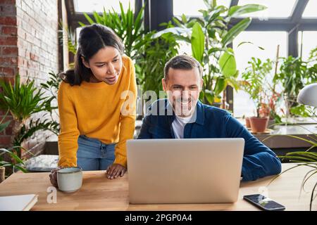 Diverse business colleagues discussing over laptop at loft office Stock Photo