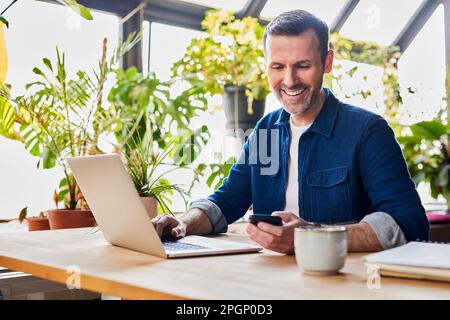 Happy businessman text messaging through smart phone at desk in loft office Stock Photo